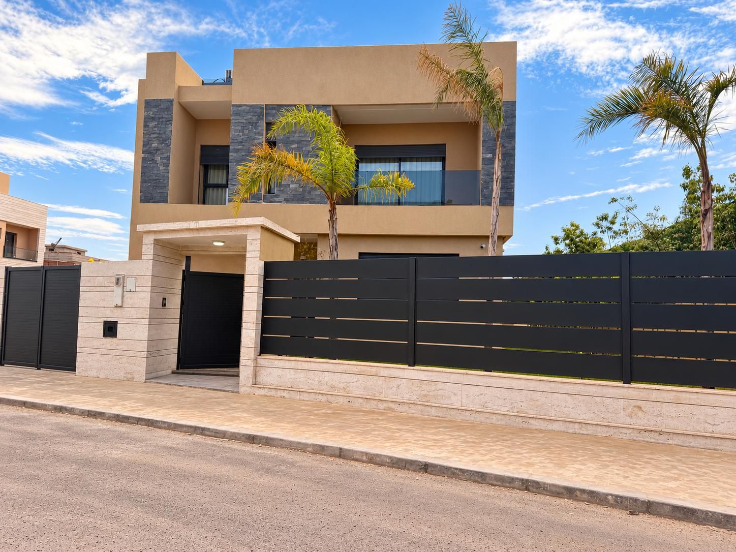 A modern two-story building with a flat roof, a gated entrance, and a paved driveway.