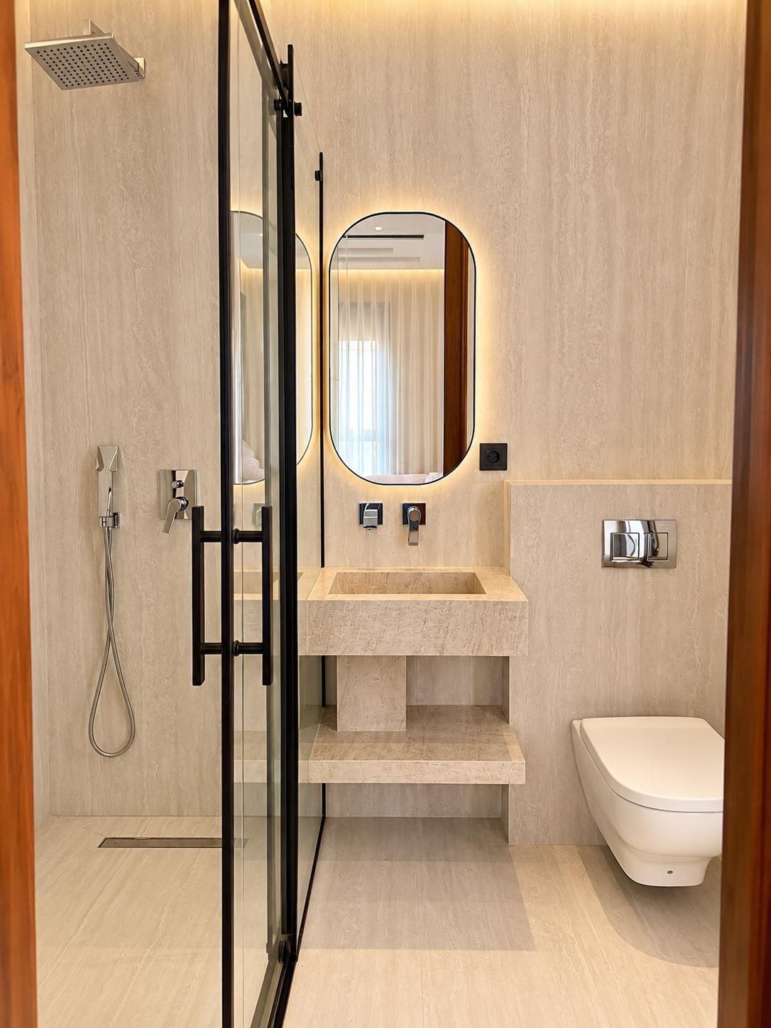 A modern bathroom with a glass shower enclosure, a sink with a mirror, and a toilet.