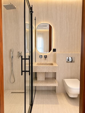 Une salle de bain moderne avec une douche à parois de verre, un lavabo avec un miroir et des toilettes.