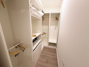 A walk-in closet with open shelves, hanging space, and a wooden floor. - Ocean View 1-Bed Apt Downtown CasaAmarilla305 (Oranjestad)