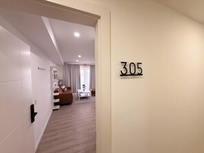 A modern hotel room with a wooden floor, a sofa, a coffee table, and a view of the living area. - Ocean View 1-Bed Apt Downtown CasaAmarilla305 (Oranjestad)