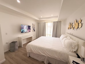 A modern bedroom with a large bed, a TV mounted on the wall, and a desk. - Ocean View 1-Bed Apt Downtown CasaAmarilla305 (Oranjestad)