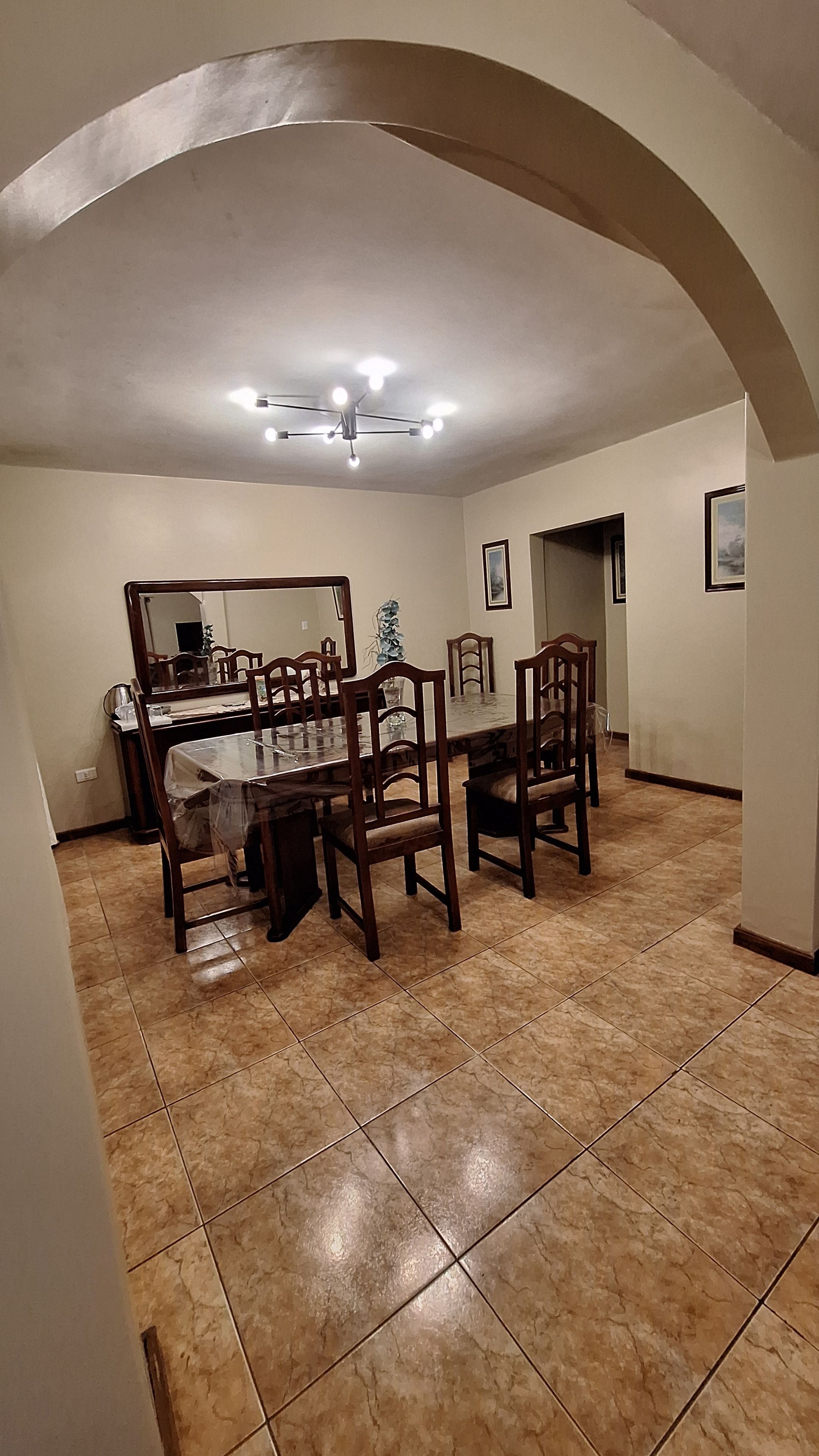 Un espace repas comprenant une table et des chaises, un ventilateur de plafond et un sol carrelé.