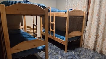 A room with three wooden bunk beds, a tiled floor, and a ceiling light.