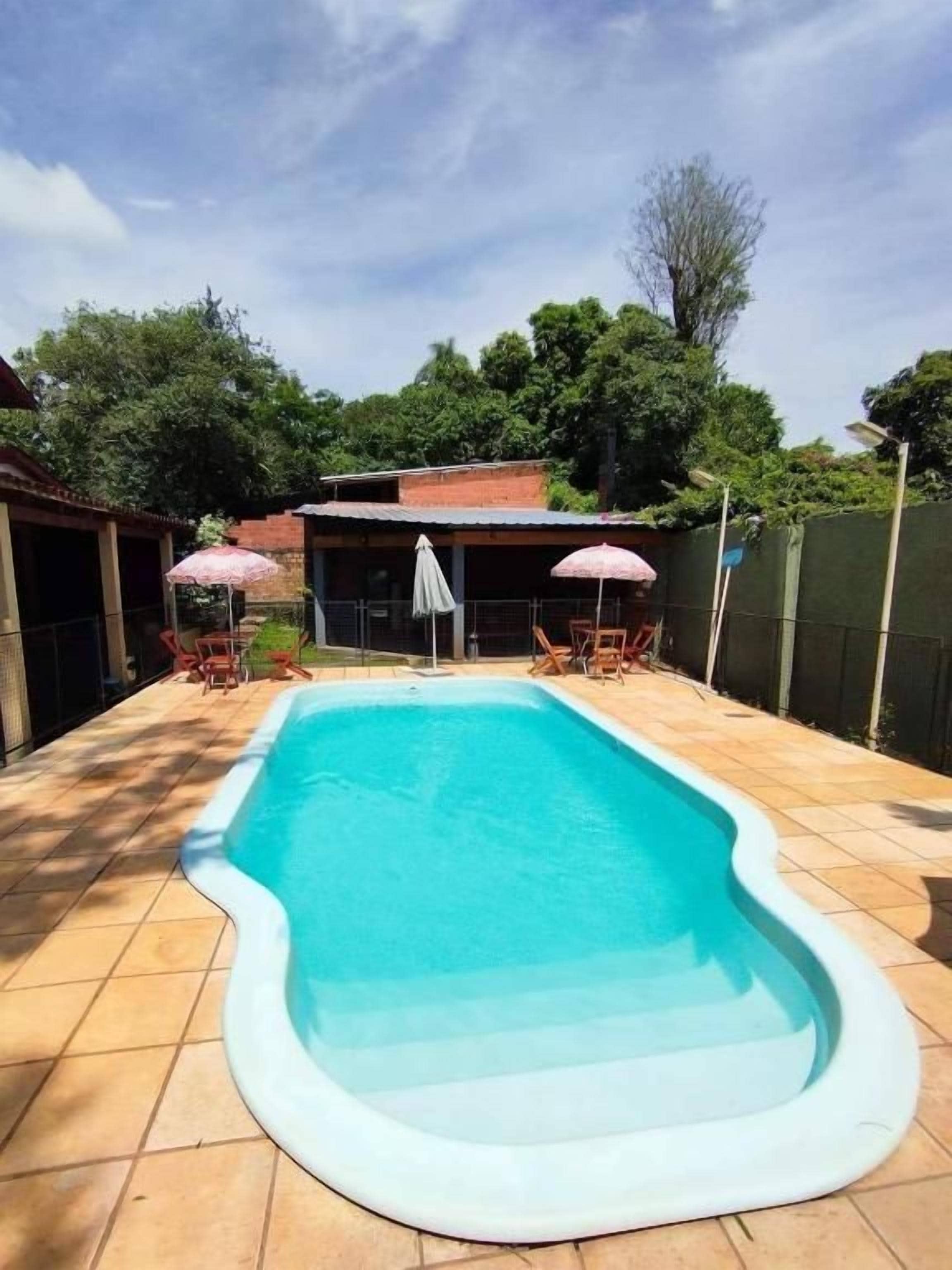 A rectangular swimming pool with a white edge, surrounded by a tiled patio.
