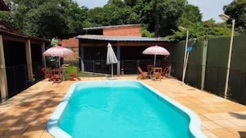 A rectangular swimming pool with a white edge, surrounded by a tiled patio.