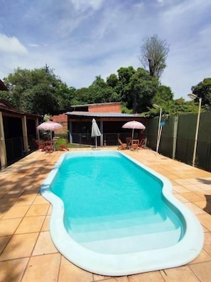 A rectangular swimming pool with a white edge, surrounded by a tiled patio. - kuri hospedaje (Puerto Iguazú)