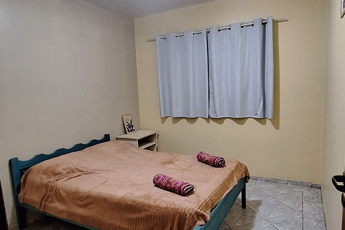 A bedroom with a bed, a nightstand, a window with curtains, and a ceiling light.