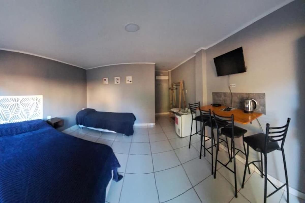 A hotel room with a bed, a desk, and a TV.
