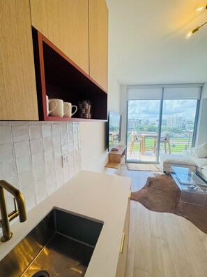 Una cocina moderna con horno integrado, un lavamanos de acero inoxidable y un amplio ventanal con vistas a la ciudad.