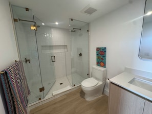 A modern bathroom with a glass-enclosed shower, a toilet, and a sink. - New 2 bedroom condo in the middle of bustling Midtown/Wynwood & Design District (Miami)