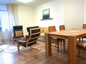 Una stanza con un tavolo da pranzo in legno, diverse sedie, un divano e una finestra con tende.