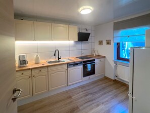 Une cuisine avec des meubles blancs, un plan de travail en bois, un four encastré et une fenêtre donnant sur un beau paysage.
