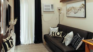 Ein modernes Wohnzimmer mit einem schwarzen Sofa, einem weißen Teppich und einem flachbildfernseher an der Wand.