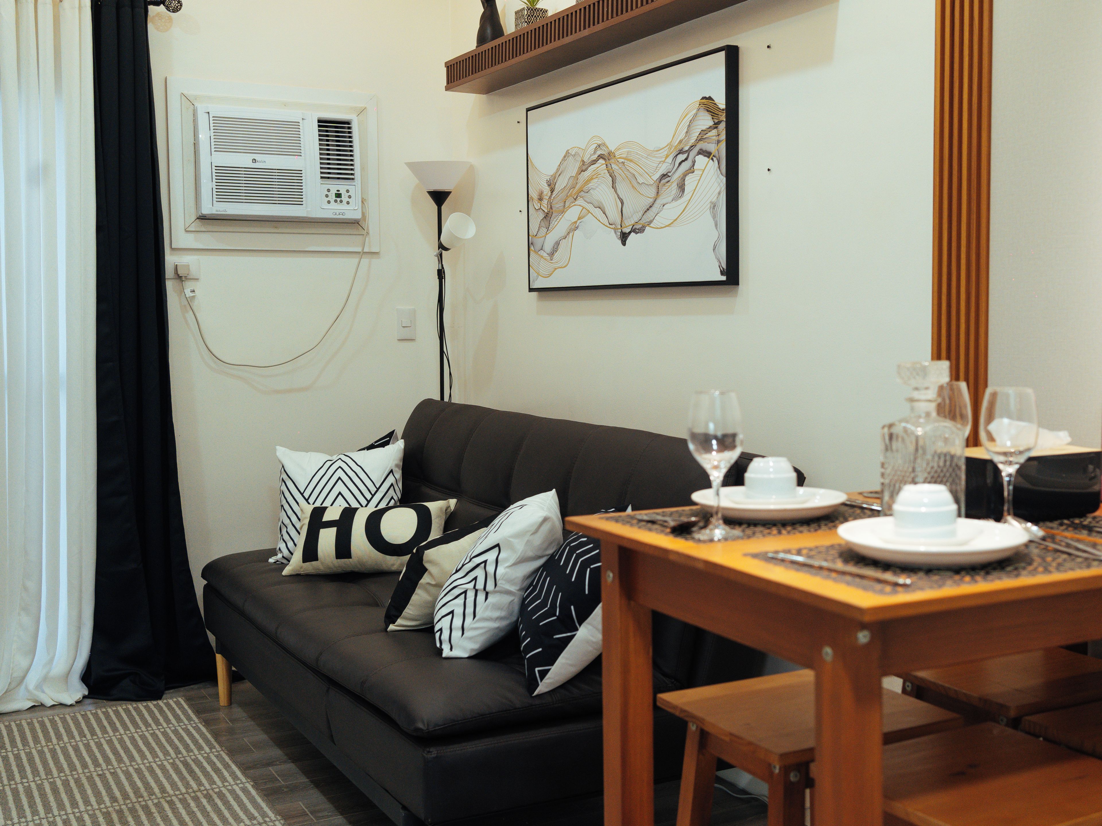A living room with a sofa, a dining table set with plates, glasses, and a candle holder.