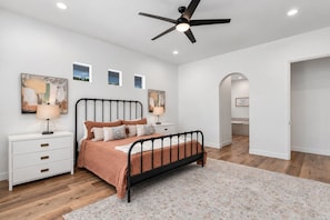 A bedroom with a bed, nightstands, a ceiling fan, and artwork on the walls. - Desert Dreamin' with Private Pool & Spa (Palm Desert)