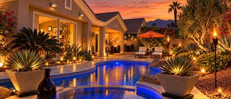 A pool area with a hot tub, surrounded by potted plants and outdoor furniture.