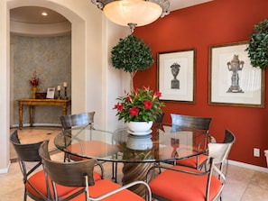 A dining area with a glass table surrounded by chairs, a potted plant, and framed artwork on the wall. - Serene 2-bedroom house with Private Pool & Jacuzzi in Rancho Mirage (Rancho Mirage)
