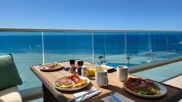 A dining table with breakfast items and a view of the ocean.