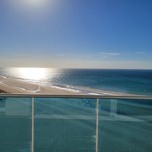 Un balcon avec vue sur une plage et l’océan.