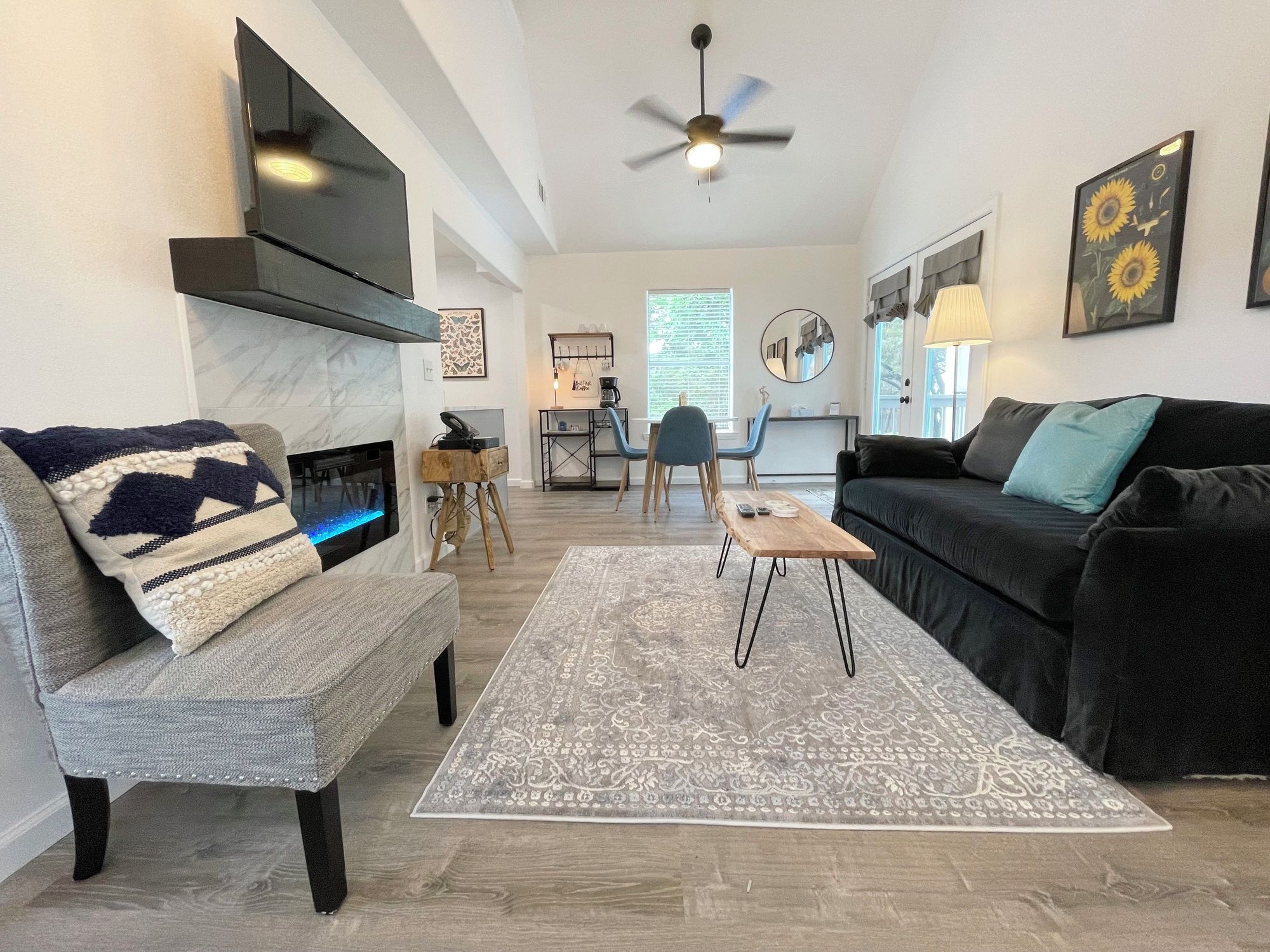 A modern living room with a fireplace, a ceiling fan, and a coffee table.