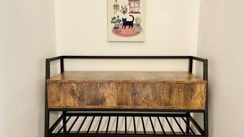 Un banc en bois doté d’une structure en métal noir, placé contre un mur sur lequel est accrochée une œuvre d’art encadrée.