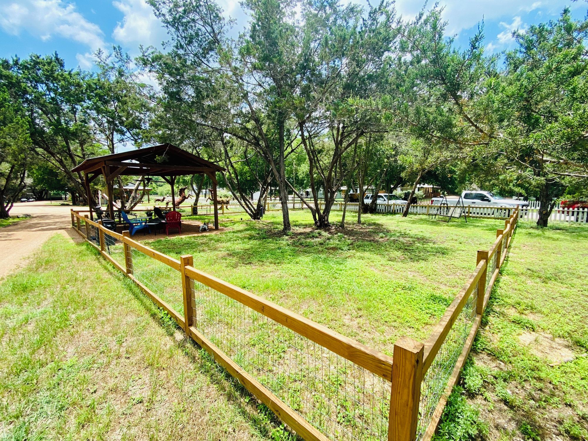 A fenced park area with a wooden pavilion and picnic tables.