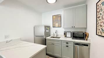 A compact kitchen with a refrigerator, microwave, and dishwasher.
