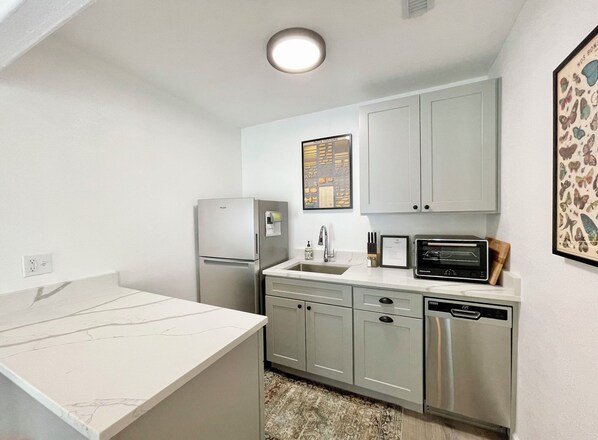 Cocina compacta con refrigerador, microondas y lavavajillas.