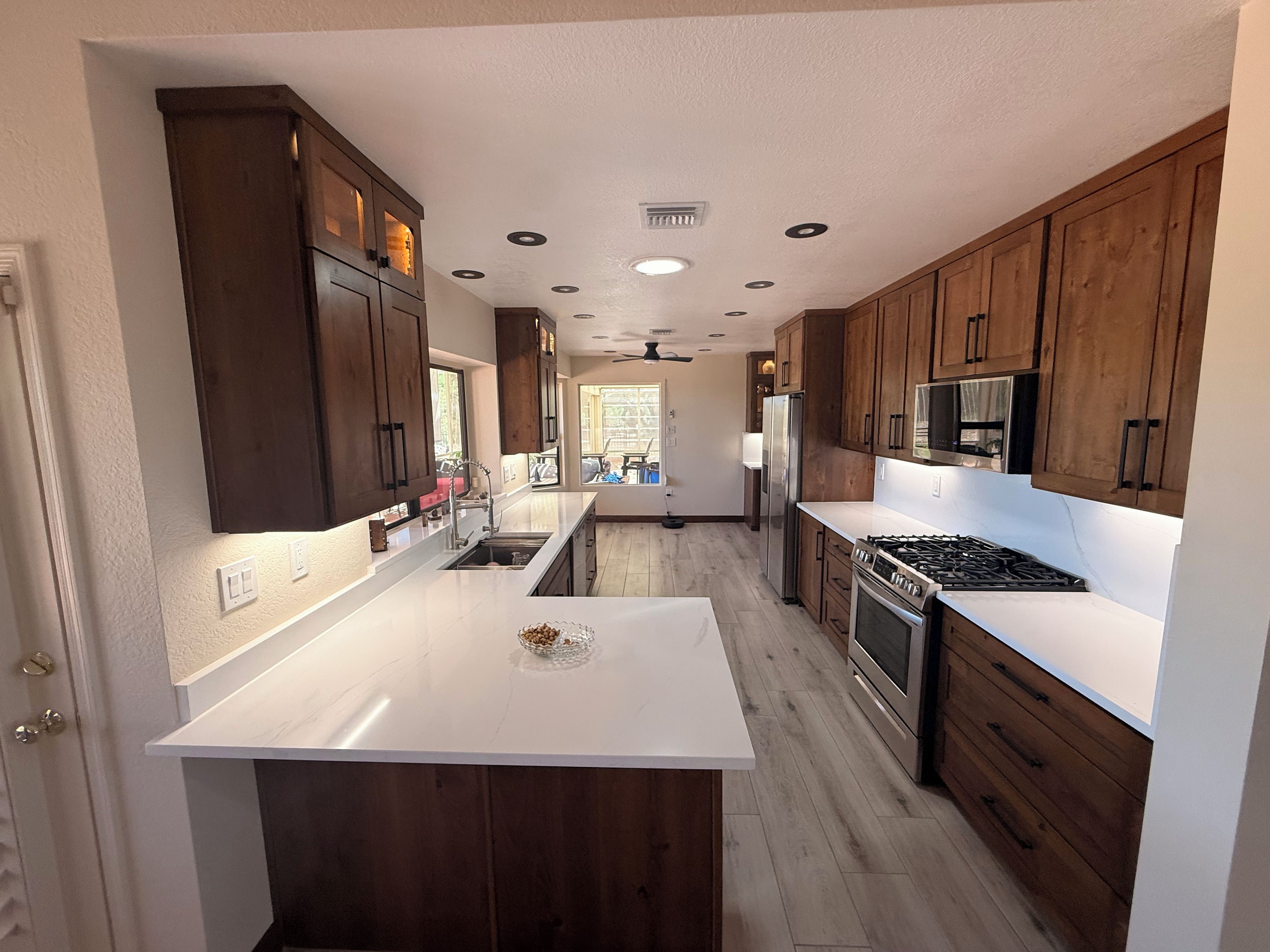 A modern kitchen with wooden cabinets, a central island, stainless steel appliances, and a view to the dining area.