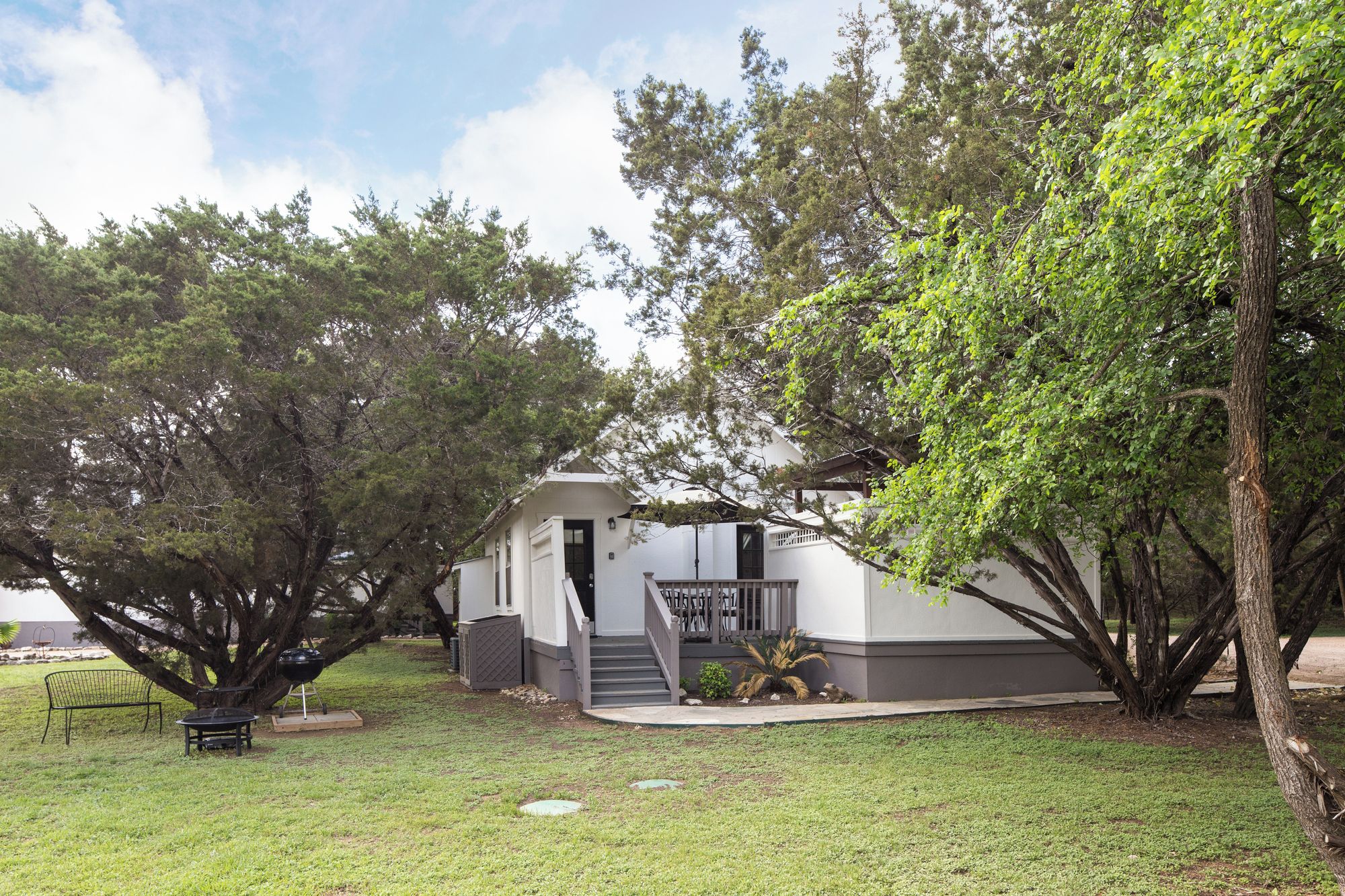 A house with a covered porch, a barbecue grill, and a small patio area.