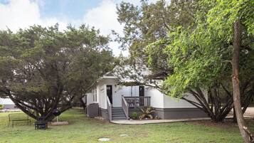 A house with a covered porch, a barbecue grill, and a small patio area.
