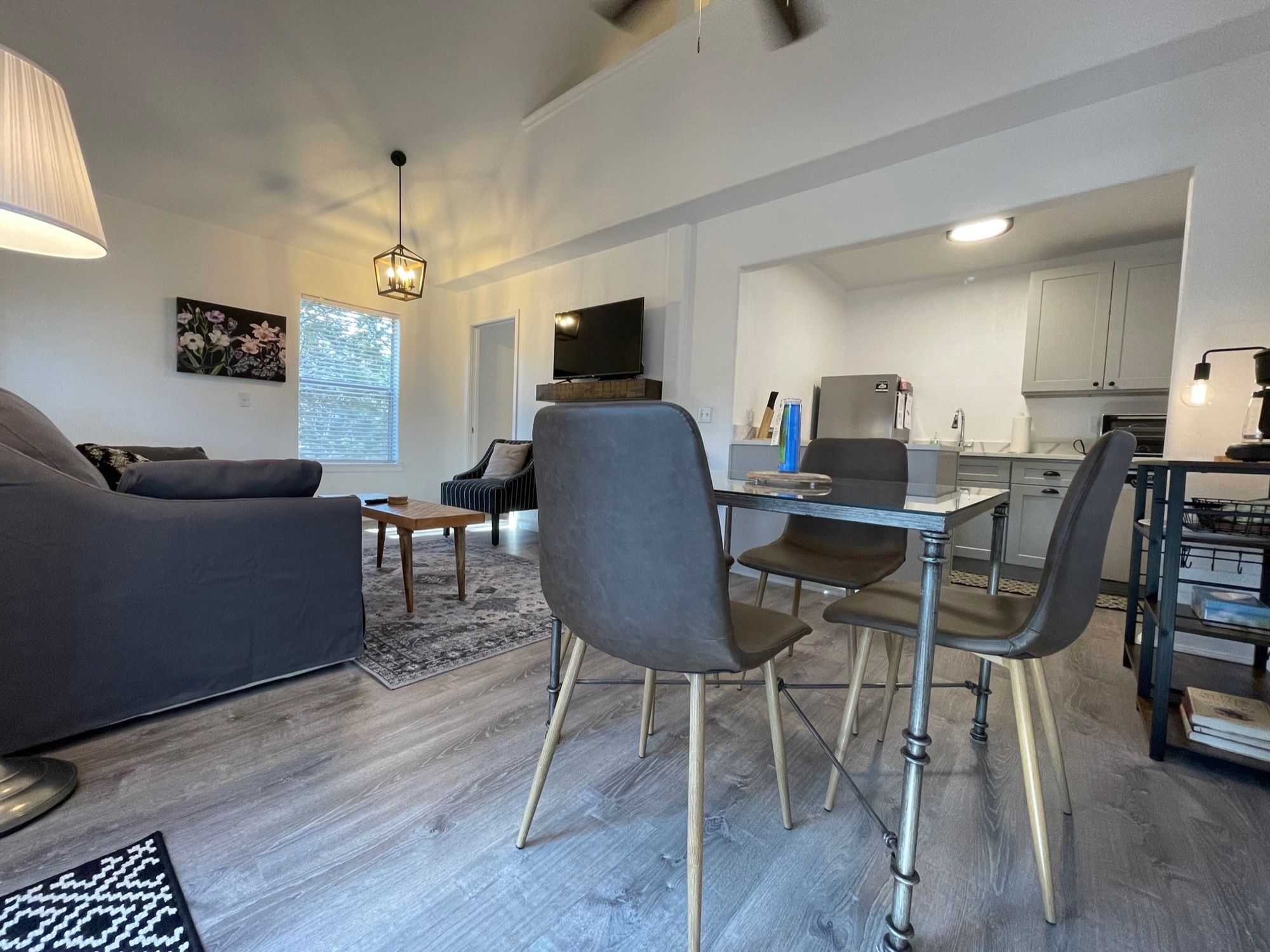 Un espace de vie moderne comprenant un canapé, une table à manger, des chaises, un téléviseur et un coin cuisine.