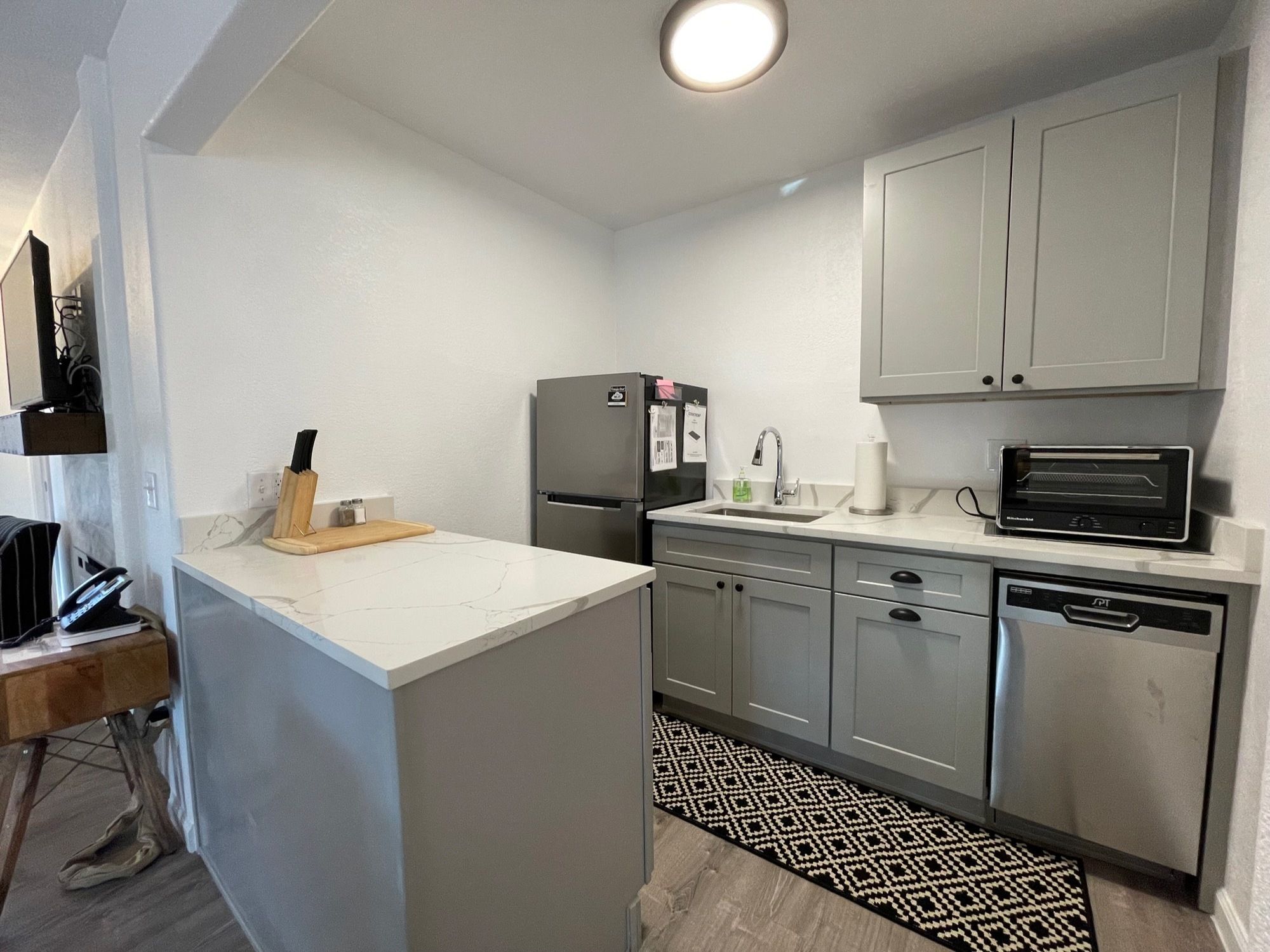 A compact kitchen with a refrigerator, microwave, and dishwasher.
