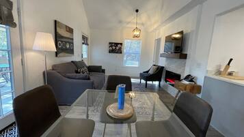 A modern living room with a dining table, sofas, and a fireplace.