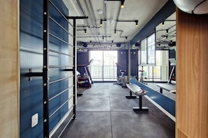 A gym with exercise equipment, a bench, and a wall-mounted rack. - Blend Oscar Freire By Housi (São Paulo)