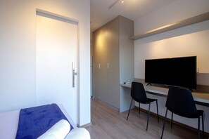 A modern hotel room with a bed, a flat-screen TV, and two chairs. - Blend Oscar Freire By Housi (São Paulo)