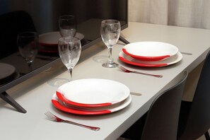 A table set with white plates, red rimmed glasses, and silver cutlery. - Blend Oscar Freire By Housi (São Paulo)