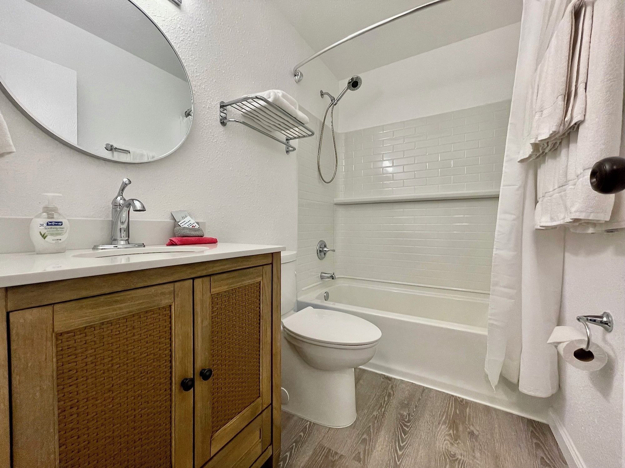 A bathroom with a wooden vanity, a toilet, a bathtub, and a shower.