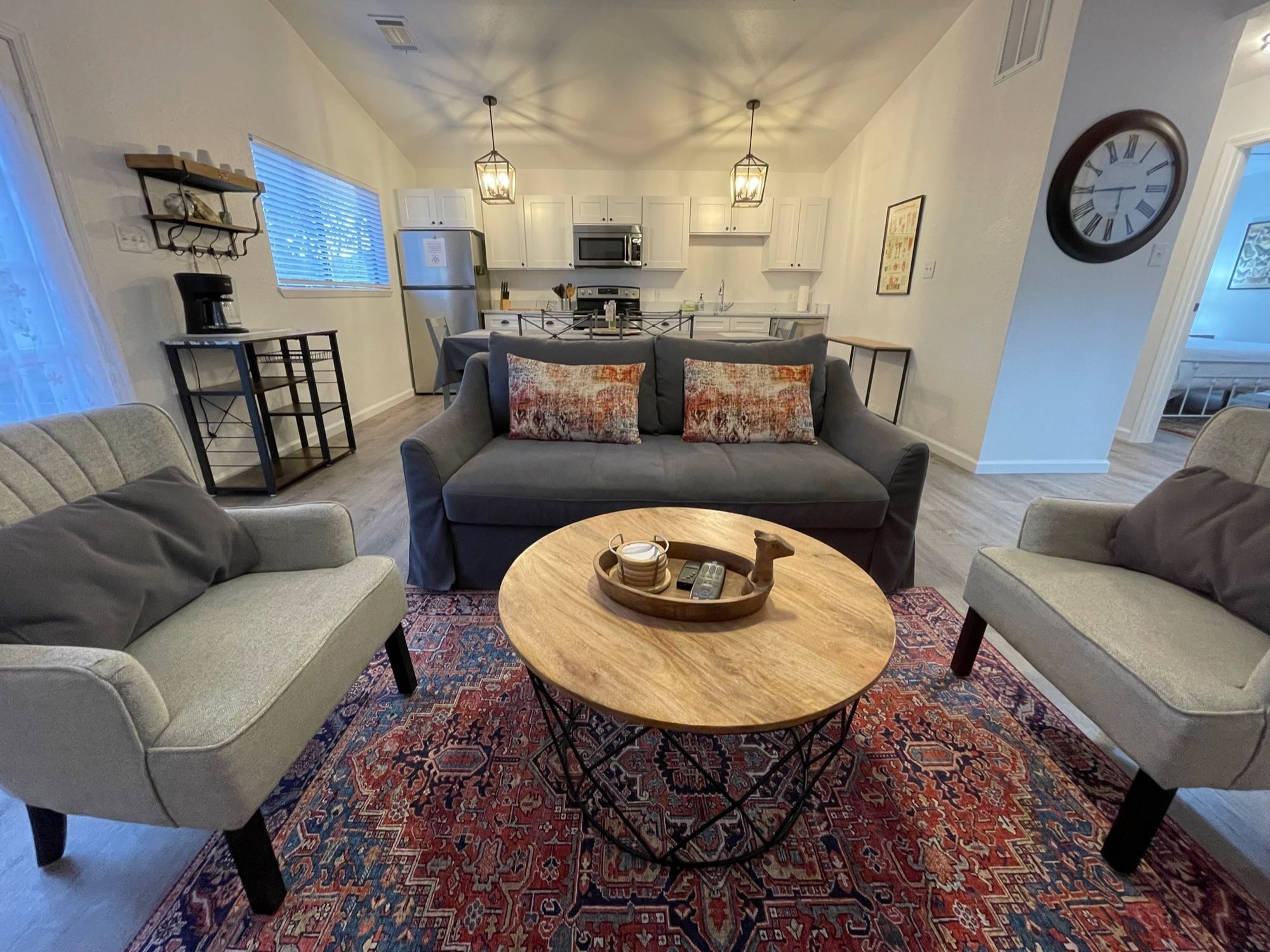 A living room with a grey sofa, two armchairs, a coffee table, and a patterned rug.