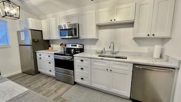 A modern kitchen with white cabinets, stainless steel appliances, and a marble countertop.