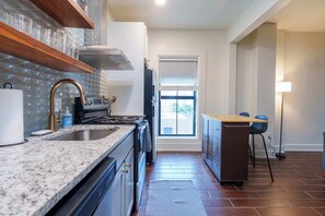 A modern kitchen with granite countertops, stainless steel appliances, and a view to the outside. - Fully Furnished Downtown One Bedroom Apartments. (Wichita)