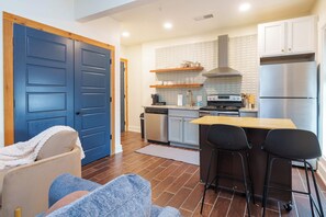 A modern kitchen with a double door, a dining area with two chairs, and a built-in oven. - Fully Furnished Downtown One Bedroom Apartments. (Wichita)