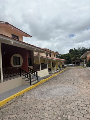 A paved street with buildings on either side, featuring a yellow curb and a staircase leading to a building entrance.