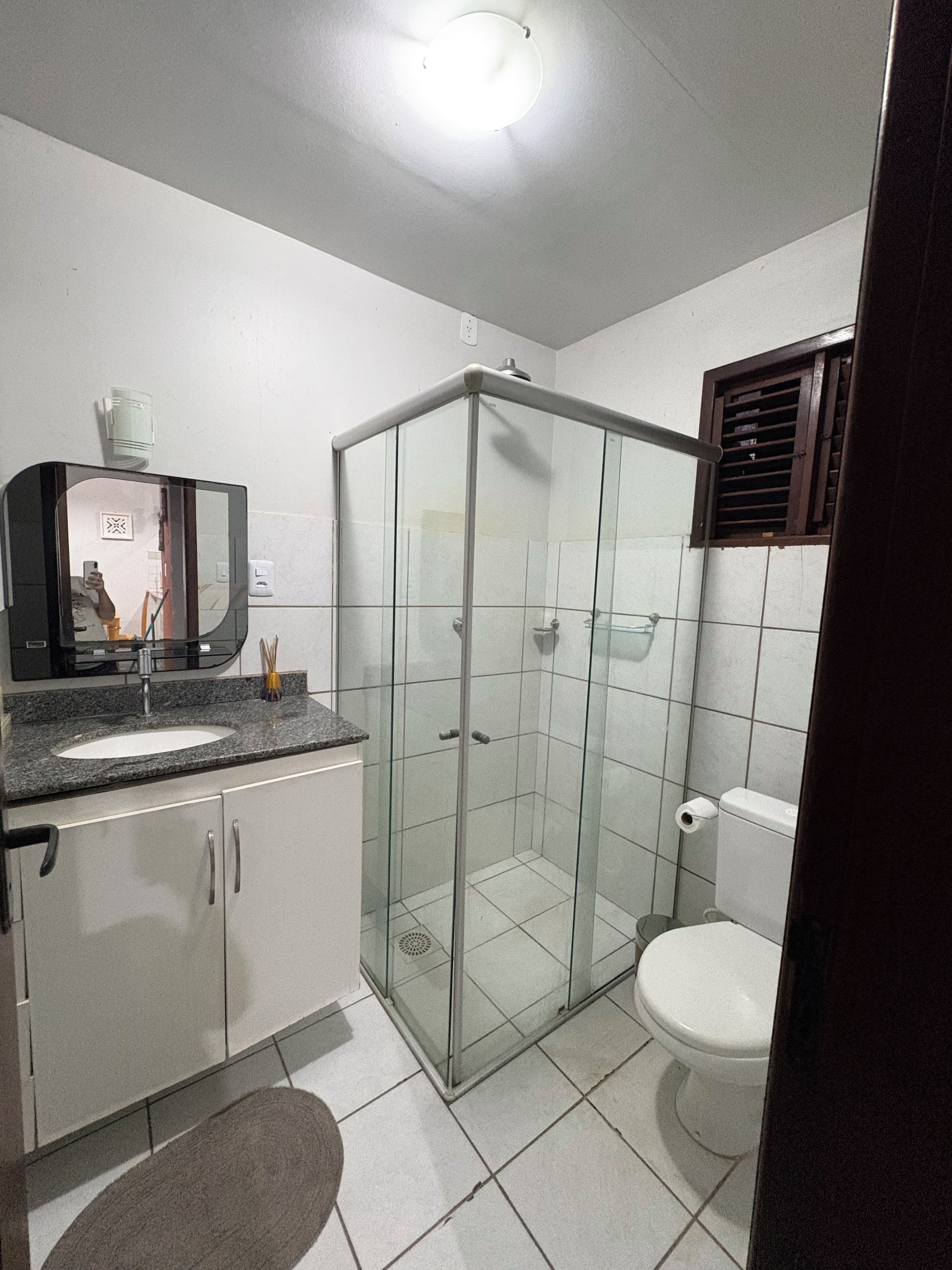 A bathroom with a glass-enclosed shower, a sink with a mirror, and a toilet.
