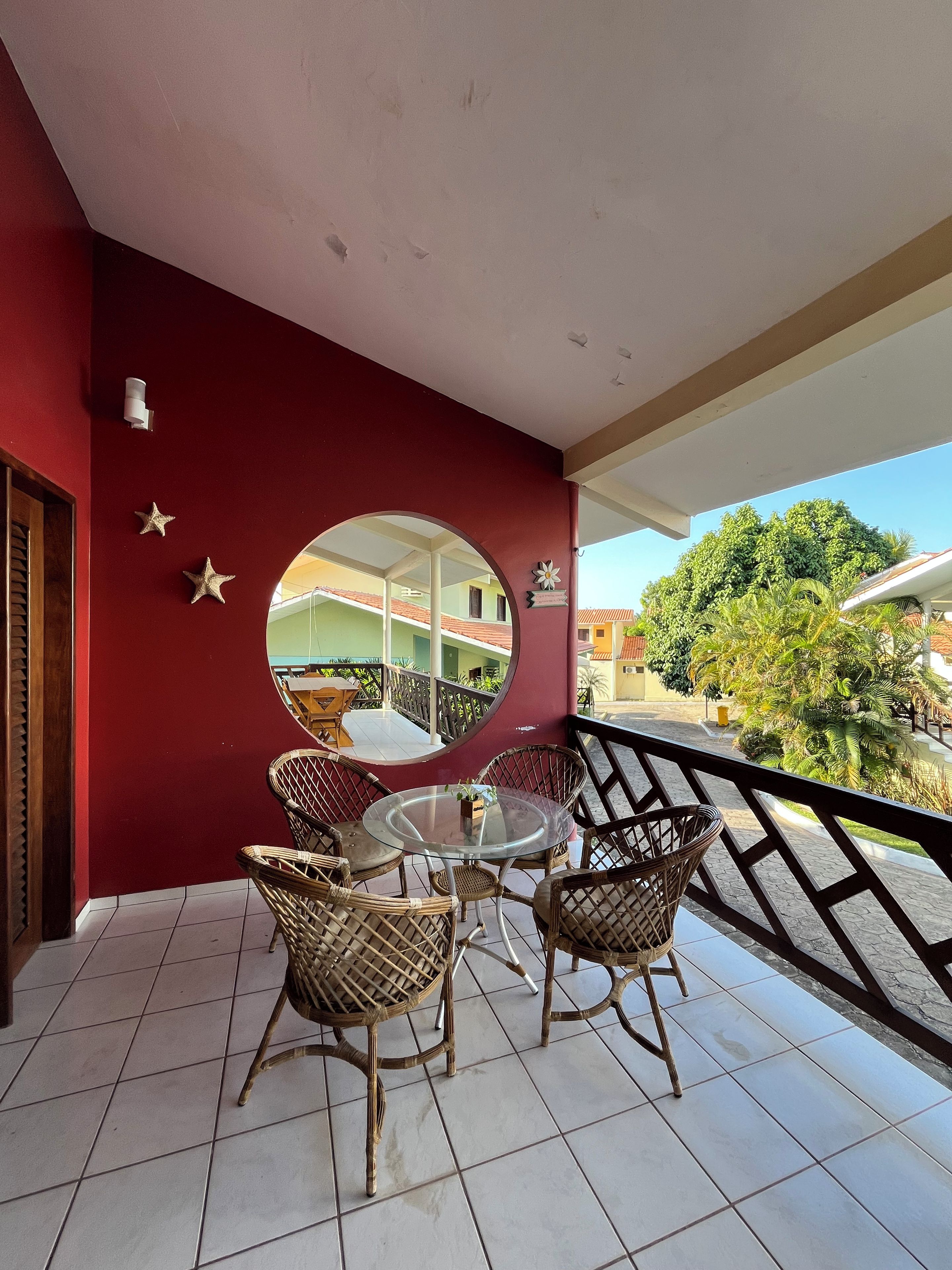 A balcony with wicker furniture, a round table, and a decorative mirror.