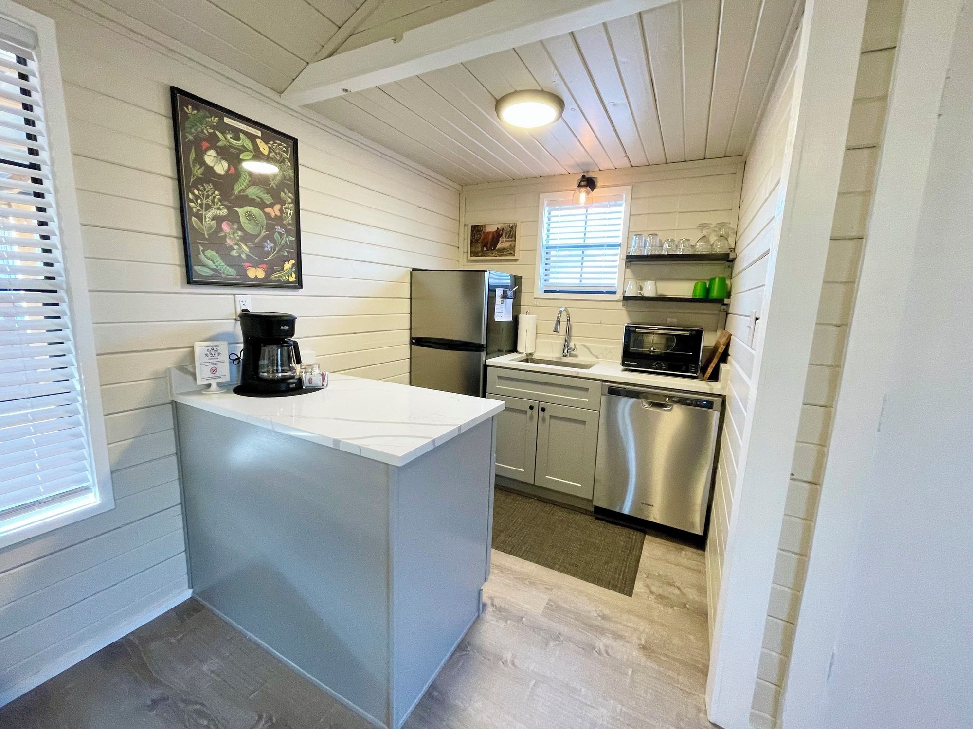 A compact kitchen with a refrigerator, microwave, dishwasher, and a coffee maker.