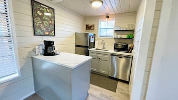 A compact kitchen with a refrigerator, microwave, dishwasher, and a coffee maker.