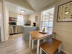 A compact kitchen with a refrigerator, stove, and coffee maker. - Cottage 12 Pewter, Pet-Friendly One-Bedroom Cottage, Private Hot Tub (Wimberley)