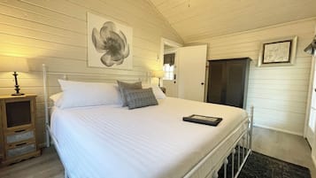 A bedroom with a bed, bedside lamps, a ceiling fan, and a door.